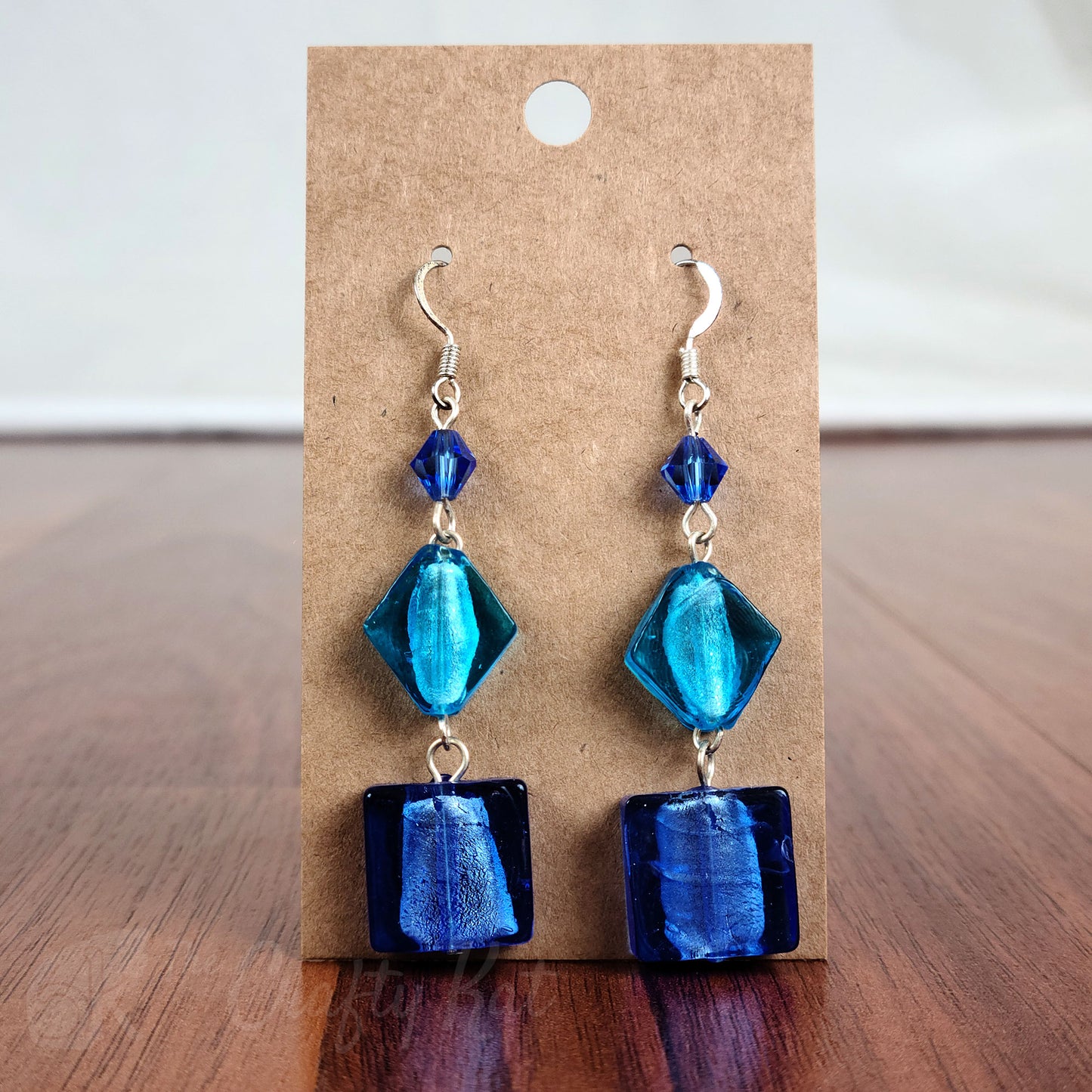 Tiered earrings made with blue and aqua foil glass and faceted crystal beads on silver fittings.