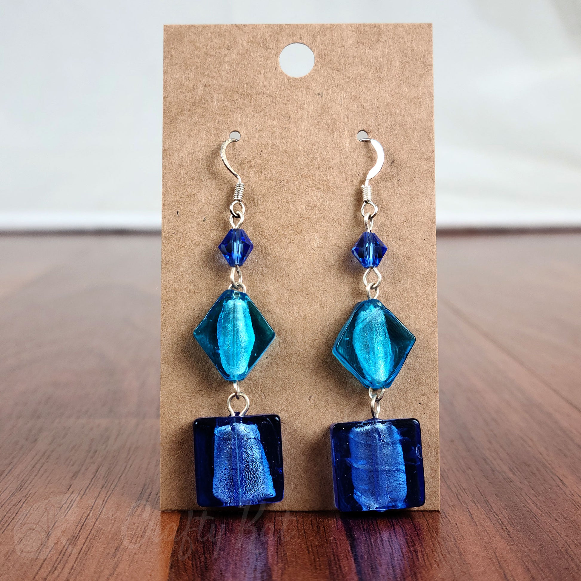 Tiered earrings made with blue and aqua foil glass and faceted crystal beads on silver fittings.