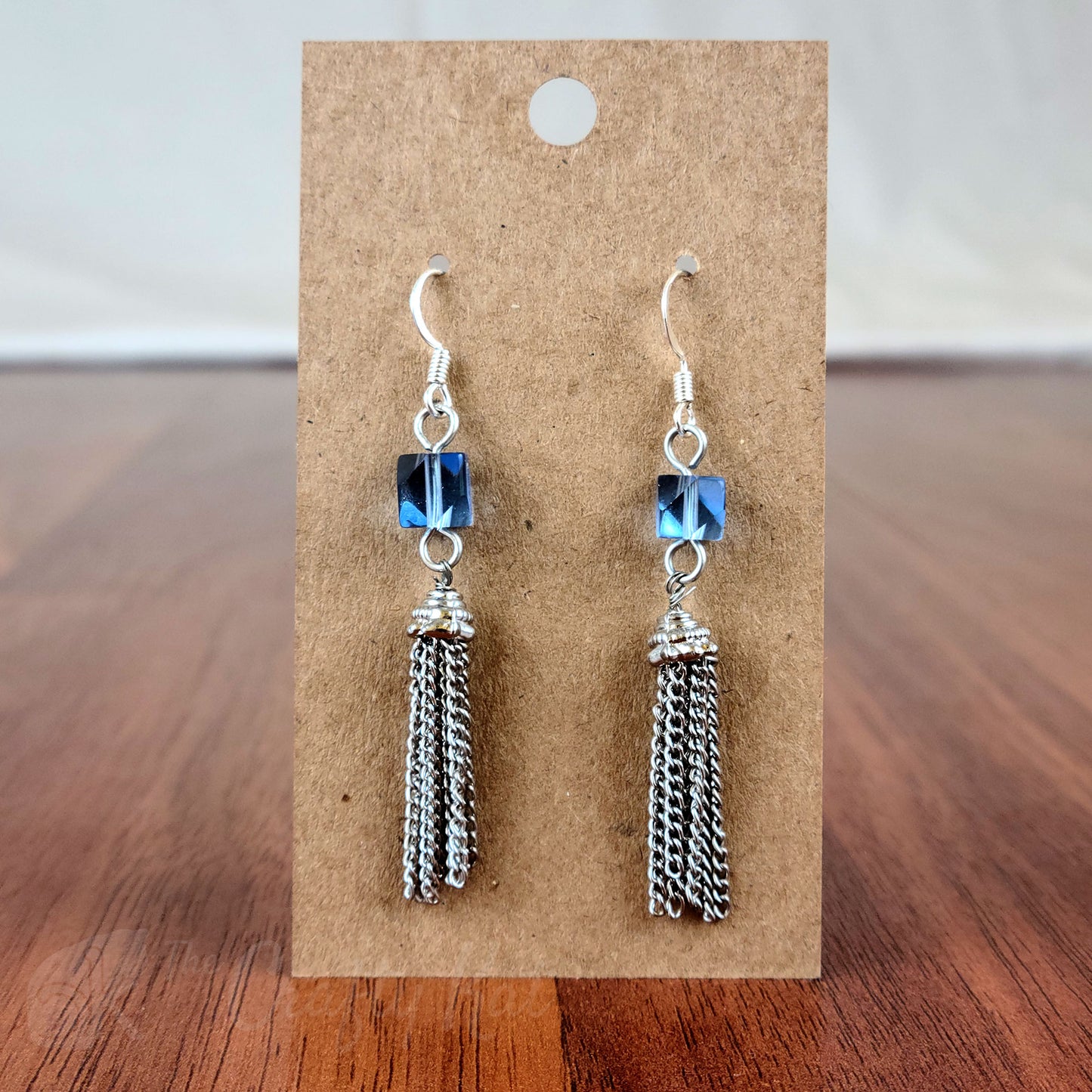 Drop earring featuring an ice blue angle-cut cube crystal bead and silver chain tassle and fittings