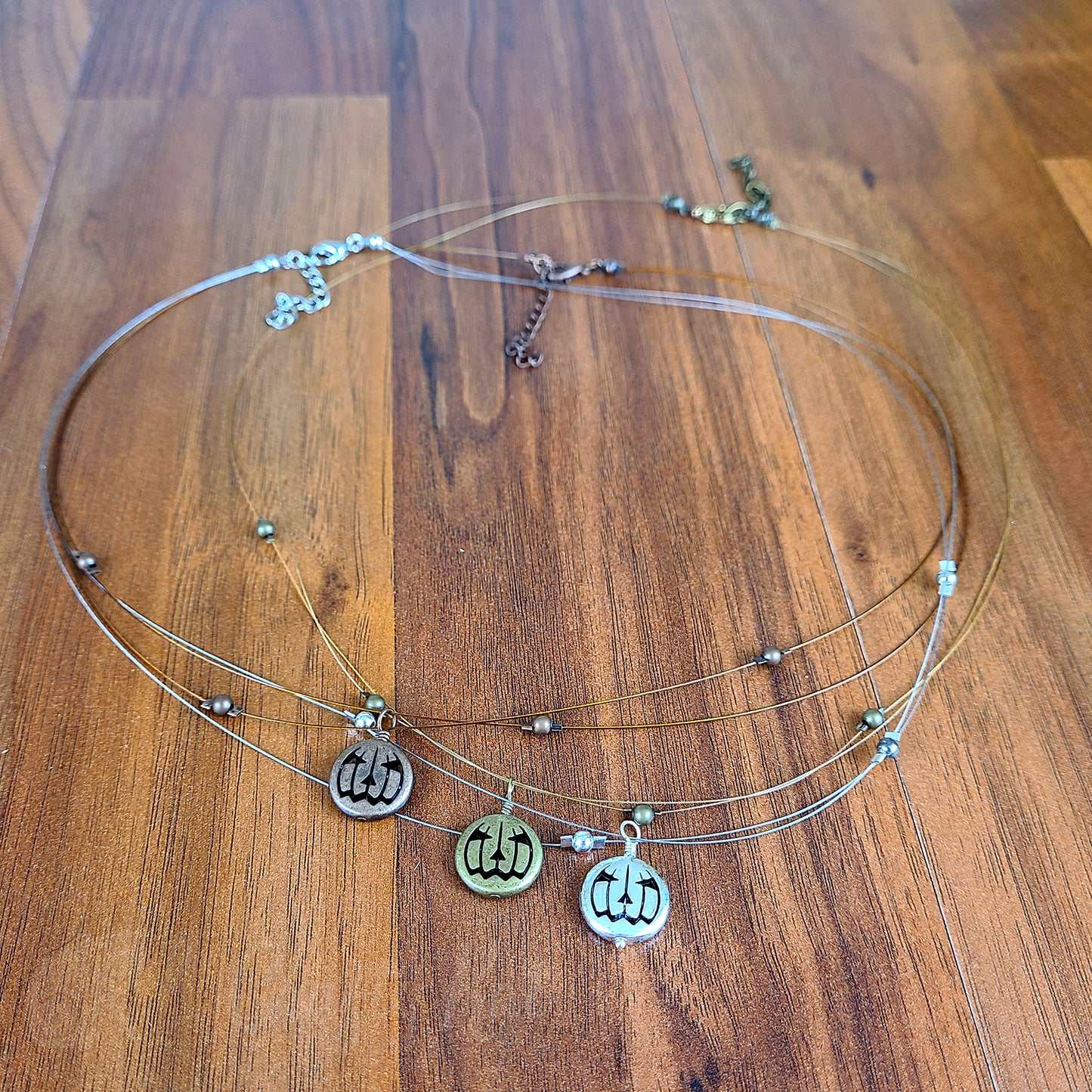 Trio of tigertail necklaces with simple round beads and jack o'lantern charms in antique copper, antique gold, and antique silver