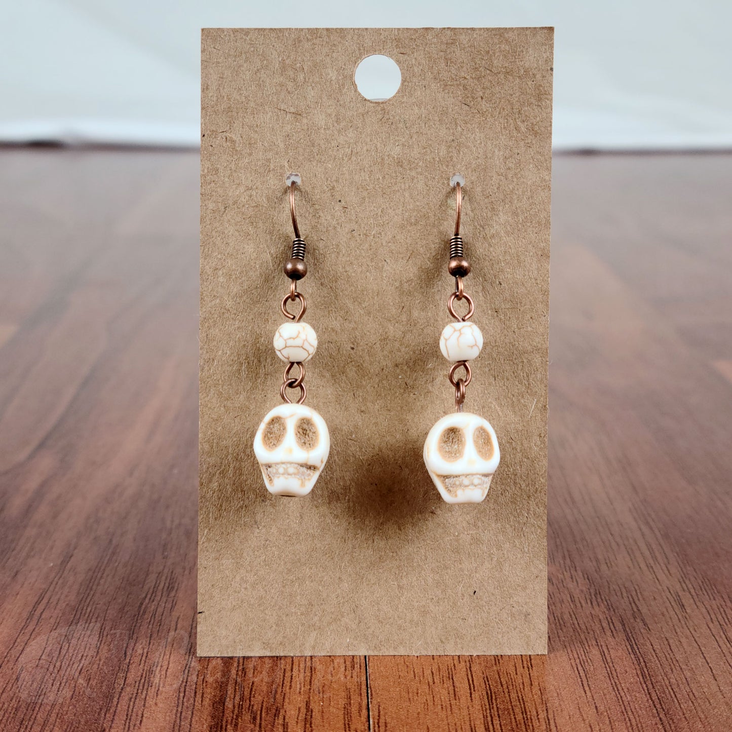 Drop earrings with white stone skulls and round beads, and antique copper hardware