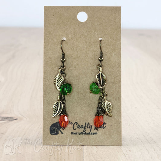 Drop earrings featuring green and orange crystals and bronze-plated leaf charms and fittings.