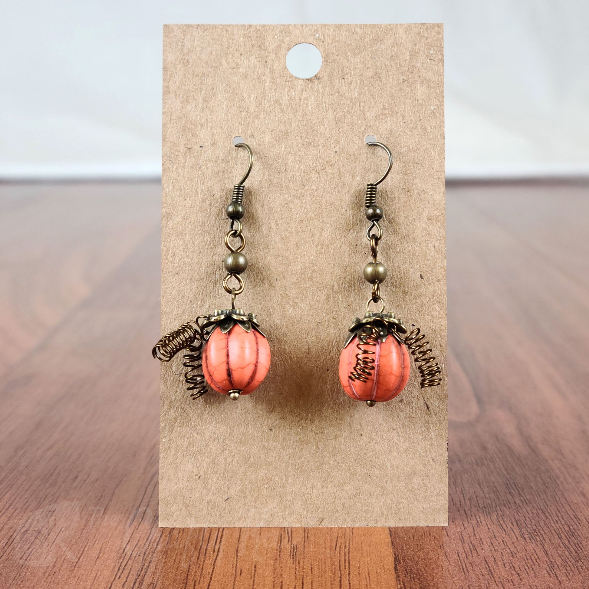 Drop earrings made of orange-dyed reconstituted turquoise corrugated beads and base metal fittings with bronze finish.