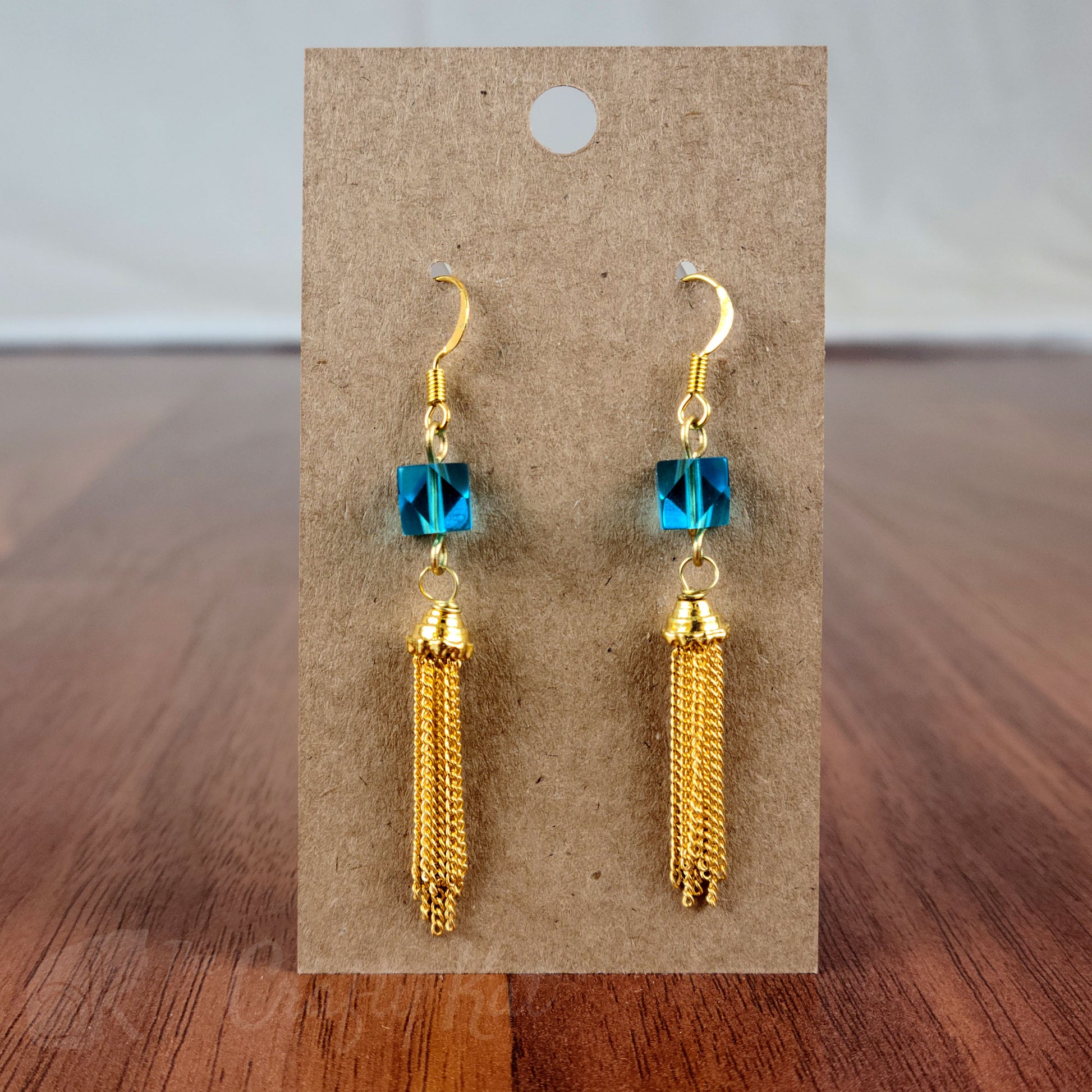 Drop earring featuring a cyan angle-cut cube crystal bead and gold chain tassle and fittings