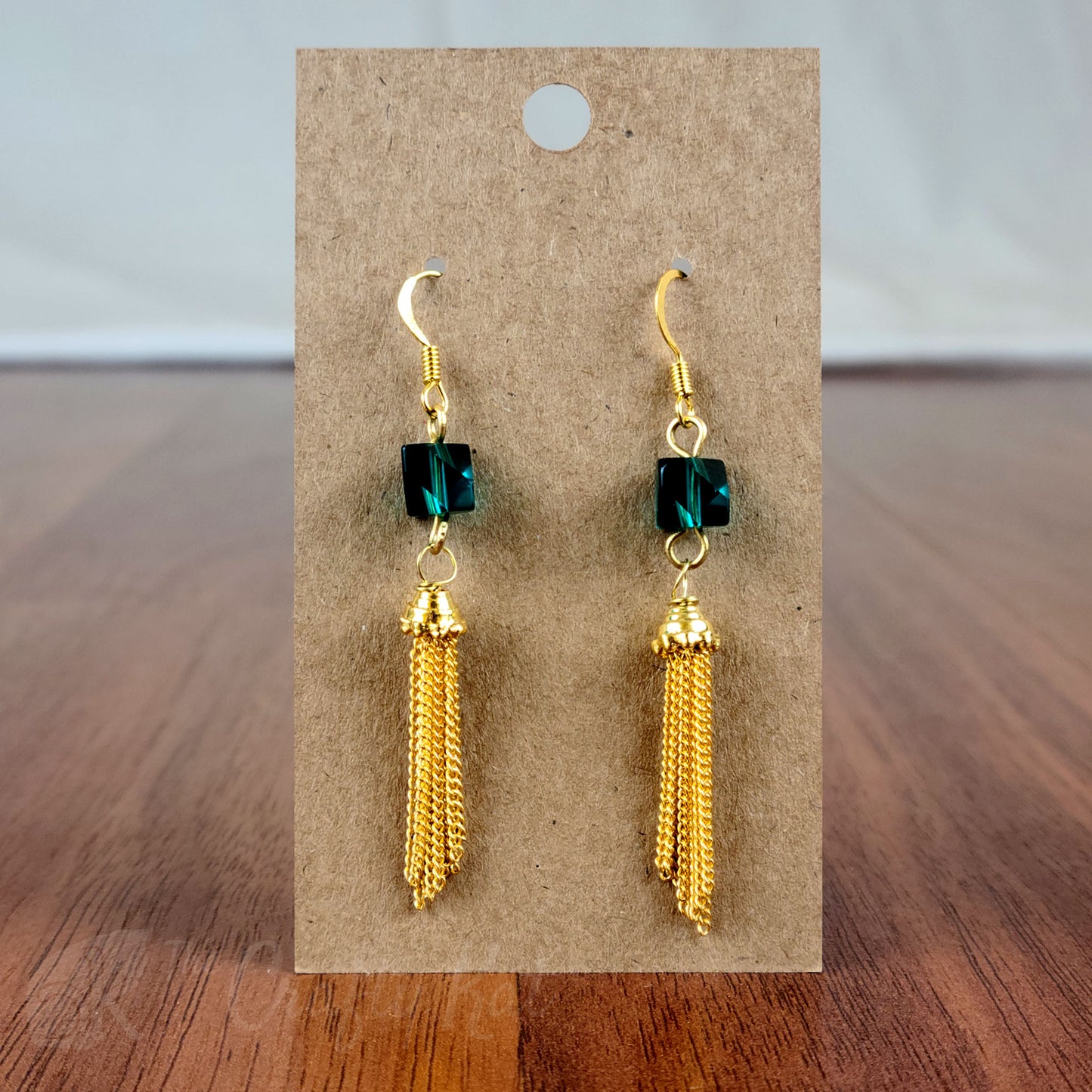 Drop earring featuring a dark teal angle-cut cube crystal bead and gold chain tassle and fittings