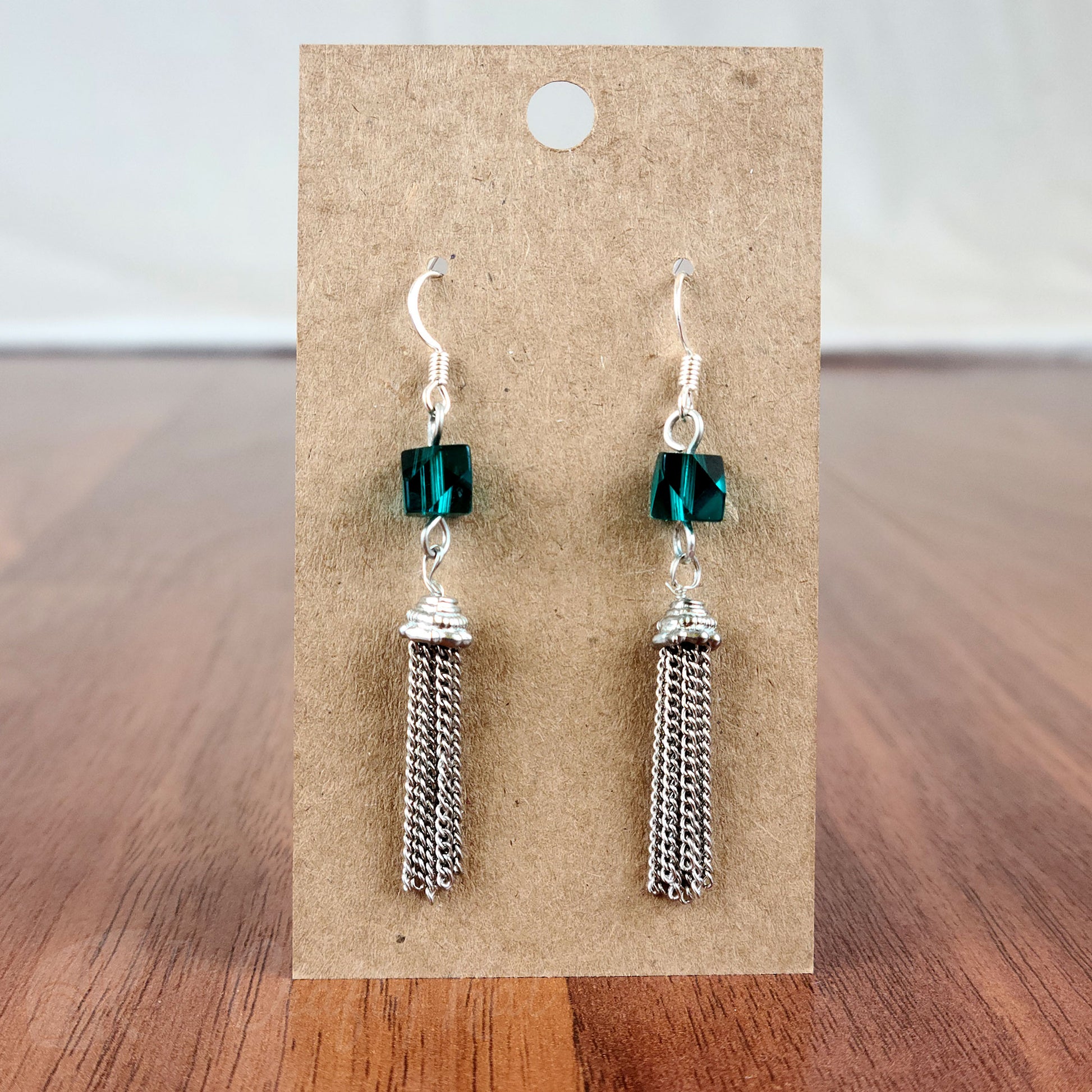 Drop earring featuring a dark teal angle-cut cube crystal bead and silver chain tassle and fittings
