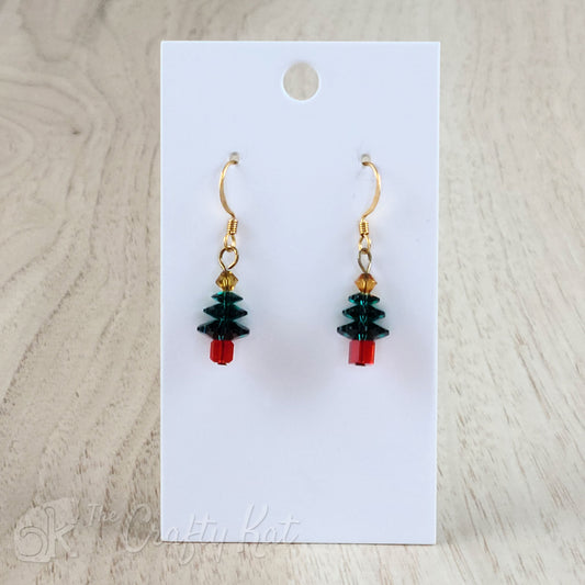 A pair of earring drops made of faceted crystal beads, each drop forming the shape of a holiday tree. This variation features a red base, emerald branches, and a gold topper on gold-plated base metal.