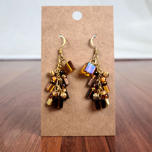 Cascading earrings made of gold, amber, and brown glass beads with gold beads and fittings