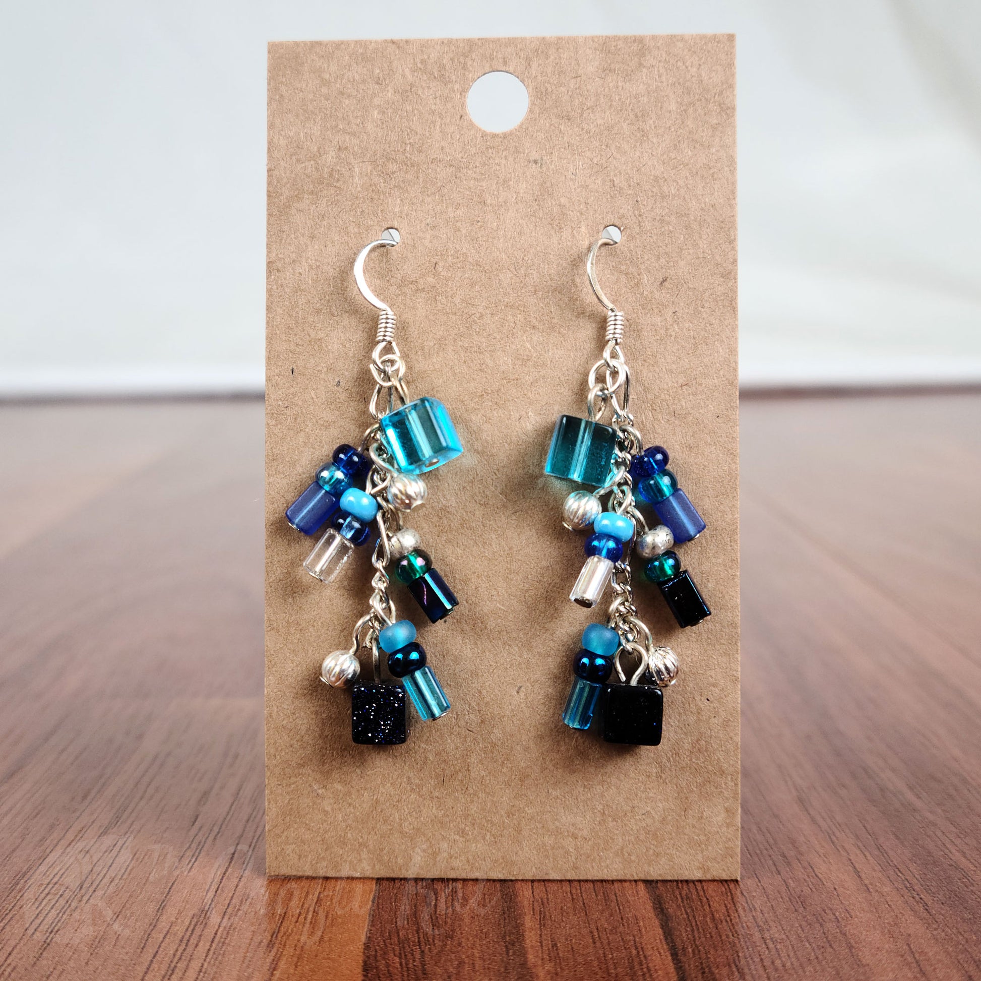 Cascading earrings made of aqua, cerulean, and navy glass, navy goldstone, and silver beads with silver fittings