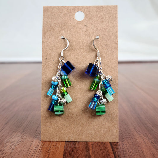 Cascading earrings made of navy, cerulean, mint, and emerald green hues of glass beads, green and blue millefiori glass beads, and silver beads and fittings
