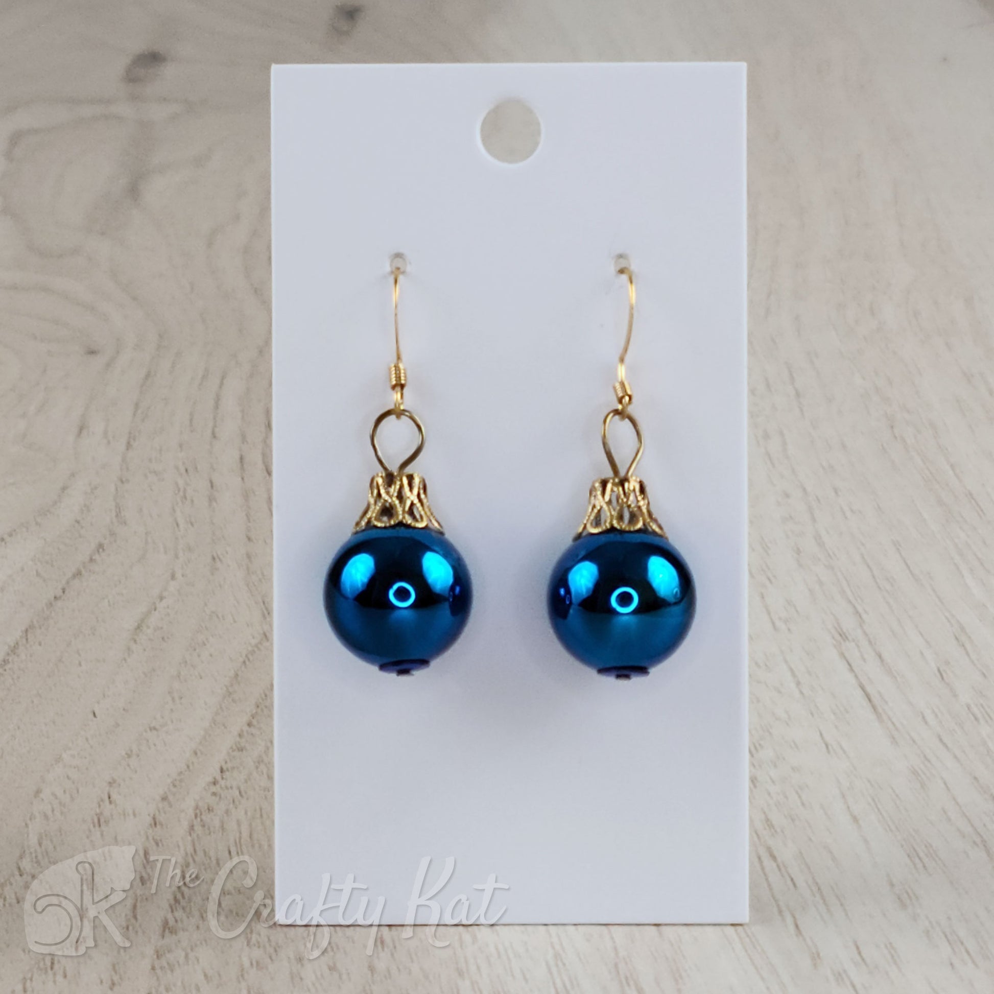 Each earring is a blue globe with a gold-plated filigree cap, giving each the appearance of a classic holiday tree ornament.