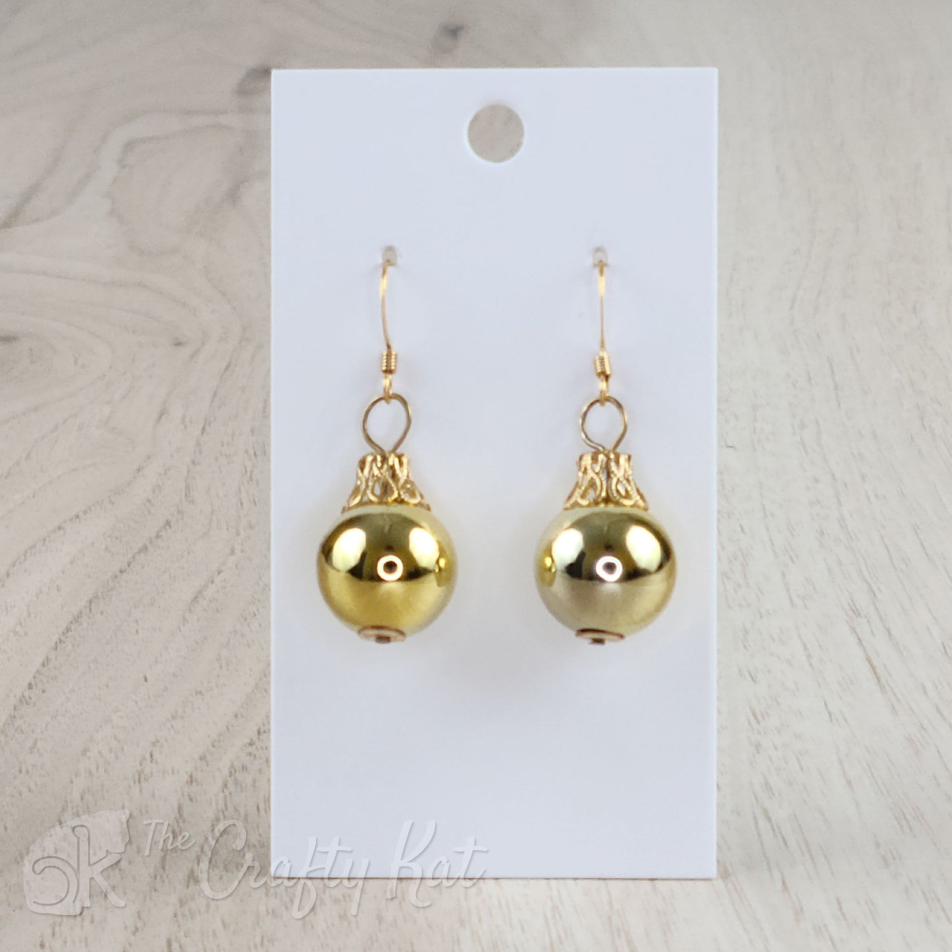 Each earring is a gold globe with a gold-plated filigree cap, giving each the appearance of a classic holiday tree ornament.