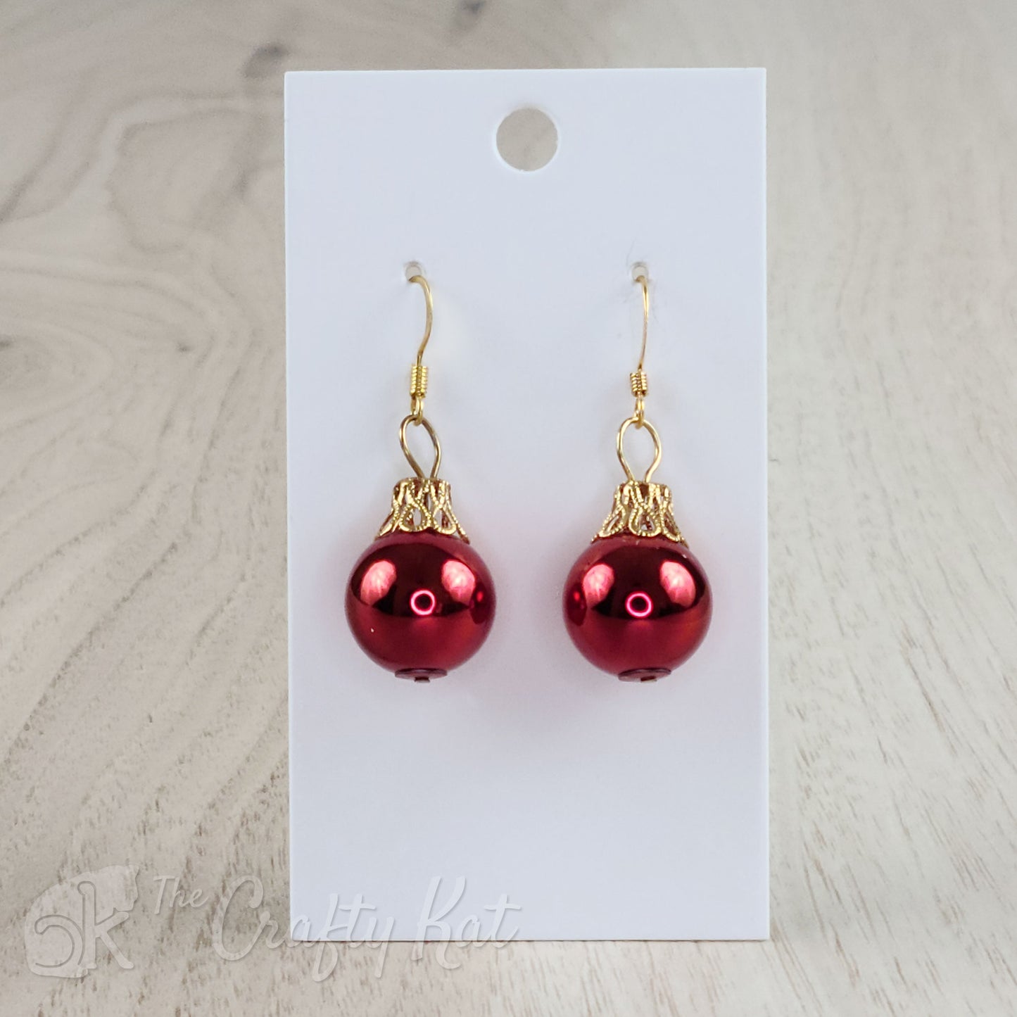 Each earring is a red globe with a gold-plated filigree cap, giving each the appearance of a classic holiday tree ornament.