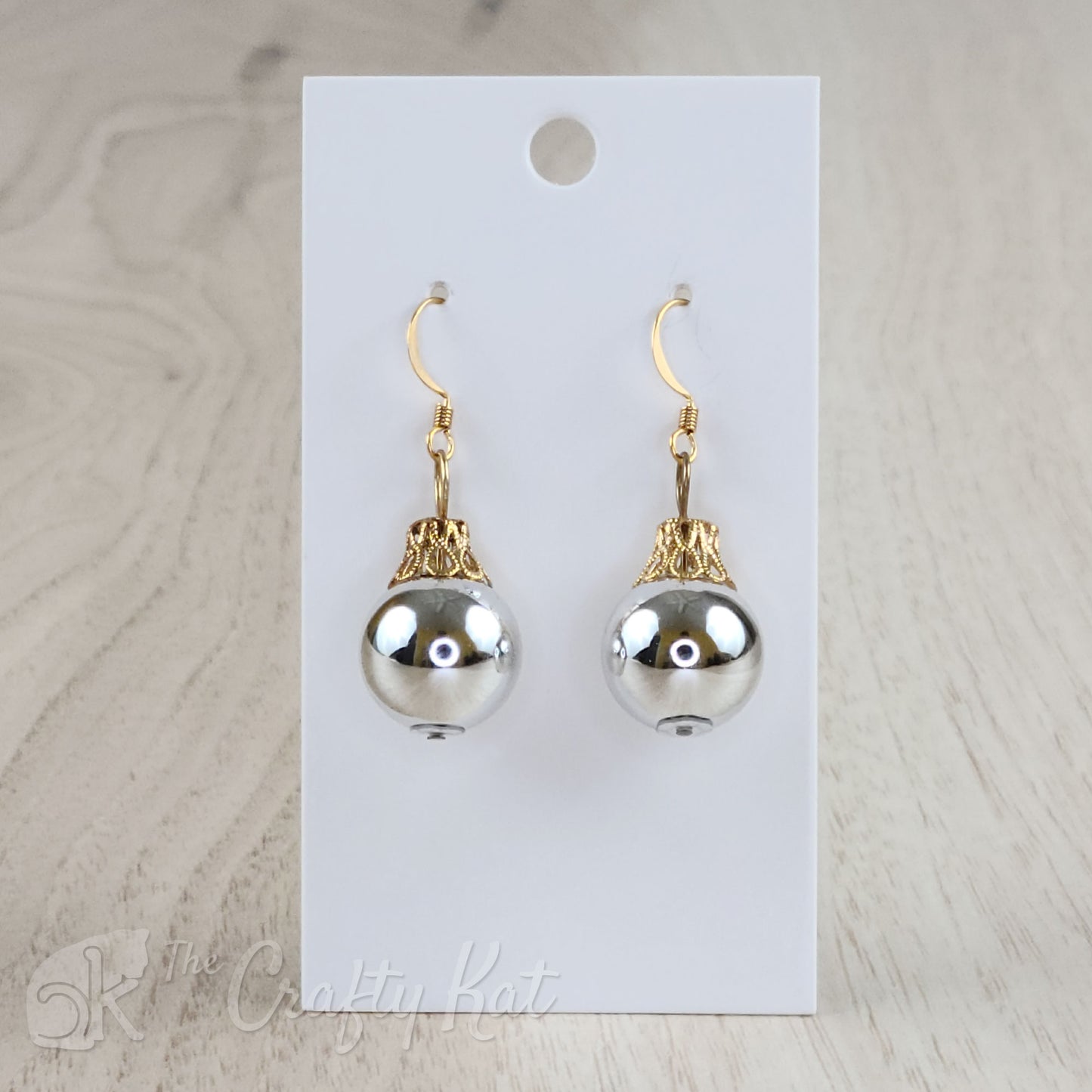 Each earring is a silver globe with a gold-plated filigree cap, giving each the appearance of a classic holiday tree ornament.