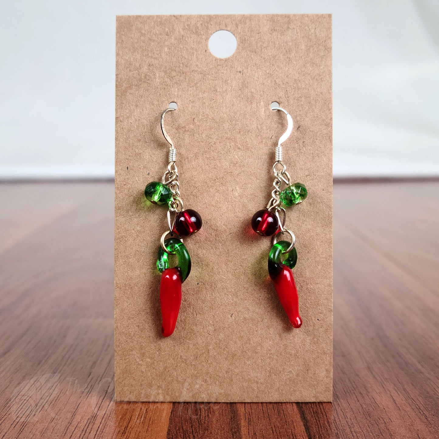 Dangling earrings made of lampwork glass chili peppers, plus green and red pressed glass beads on silver fittings