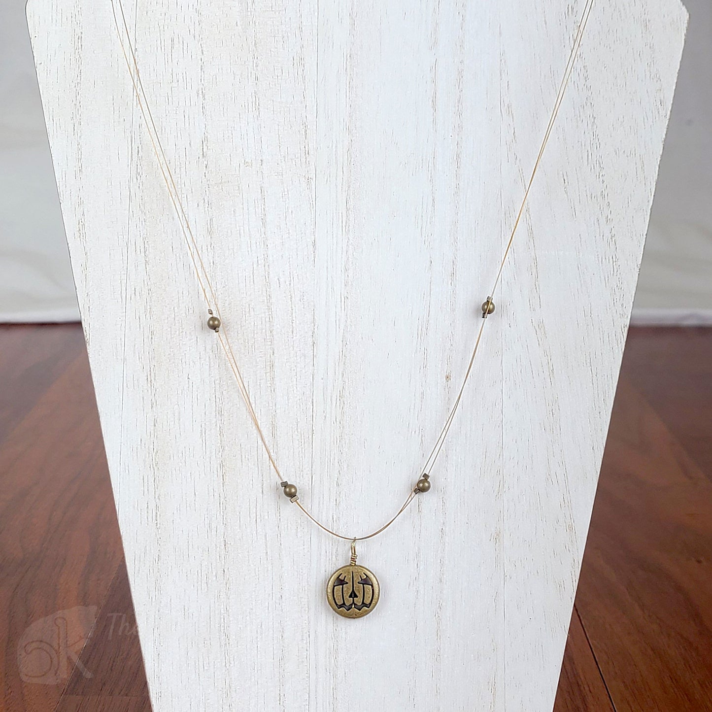 Tigertail necklace with simple round beads and jack o'lantern charms in antique gold