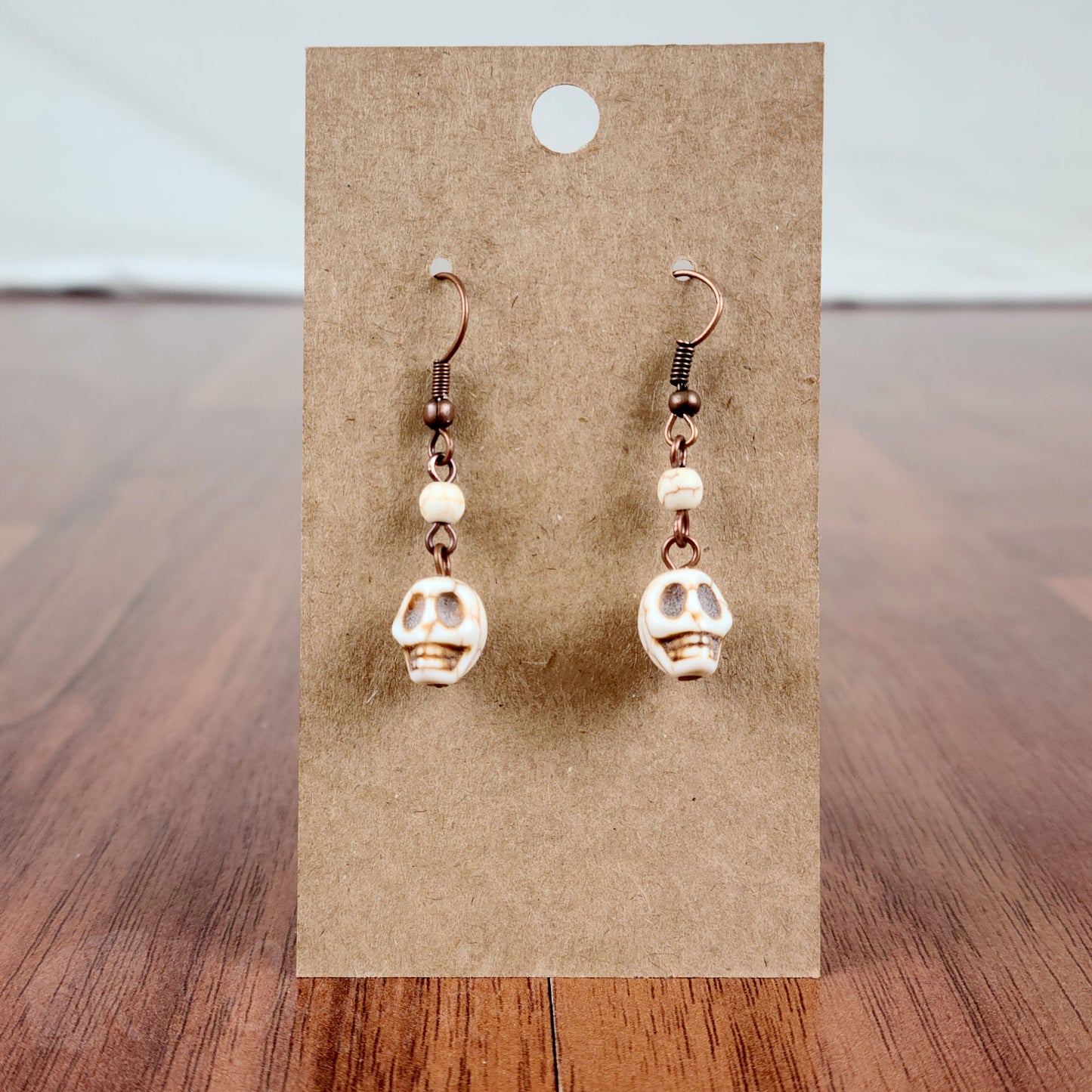 Drop earrings with white stone skulls and round beads, and antique copper hardware
