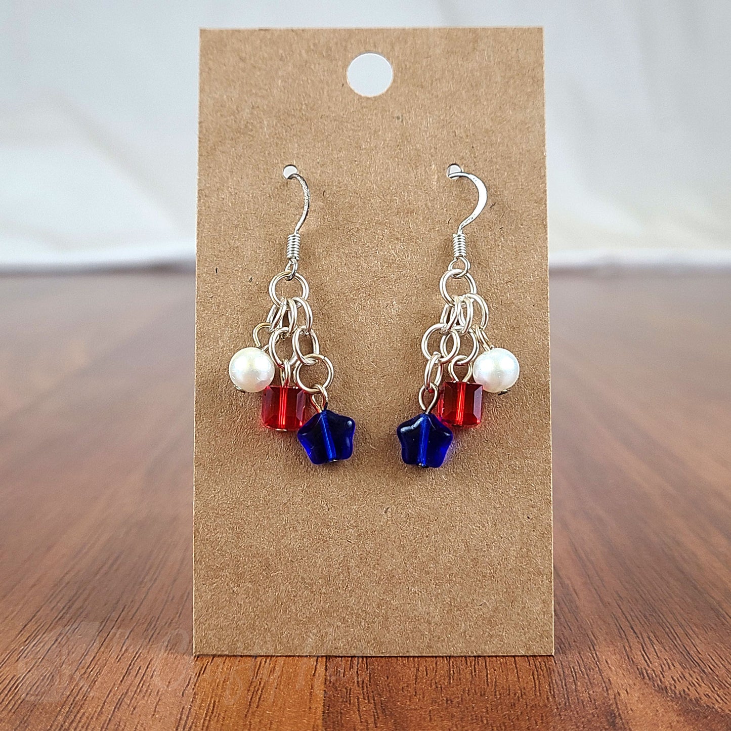 Chandelier earrings featuring blue pressed glass stars, red facet-cut crystal cubes, and white glass pearls with silver fittings