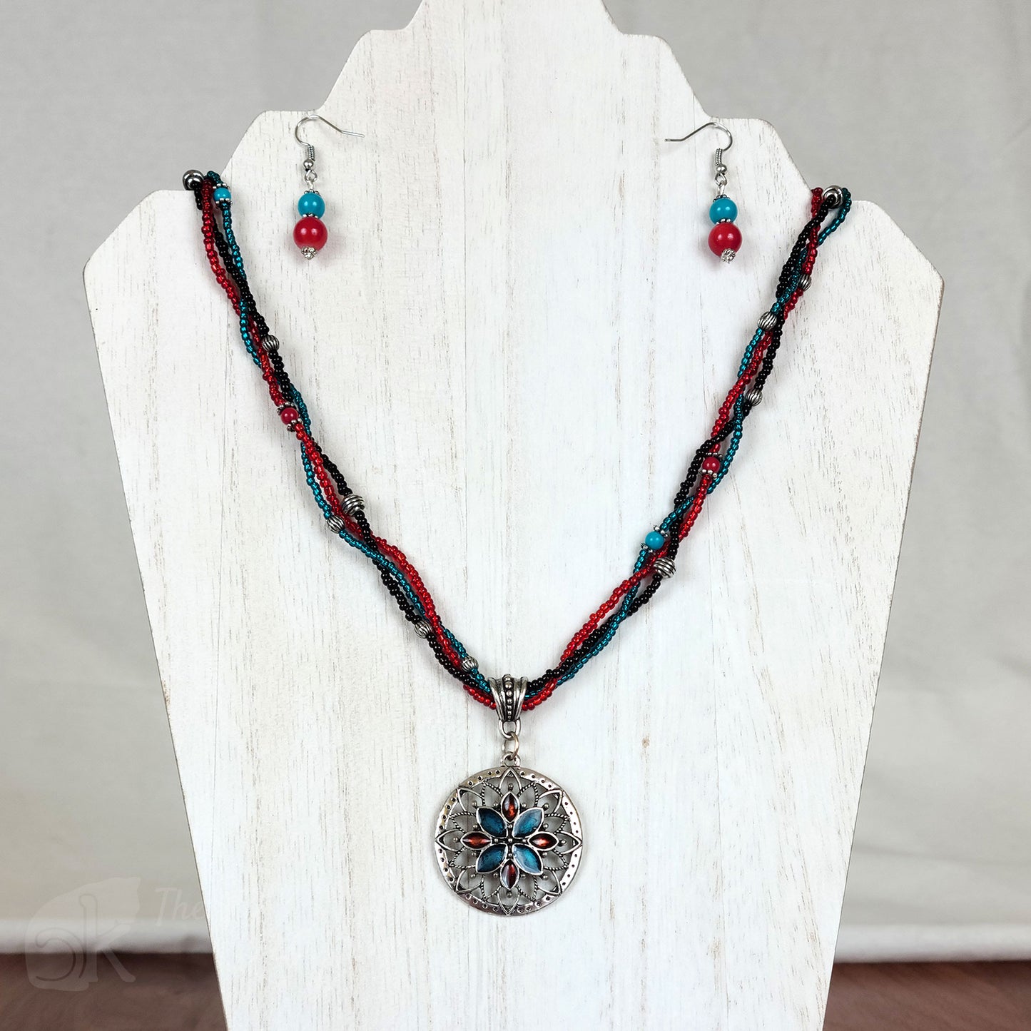 Strands of turquoise, red, and black glass seed beads loosely braided into a strand supporting an antique silver flower pendant filled with turquoise and red enamel; matching turquoise and red resin bead earrings
