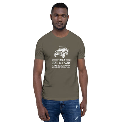 Model wearing Army (olive tan) t-shirt with distressed graphic of old military jeep and text "Original YEAR model HIGH MILEAGE some restoration MOST PARTS IN WORKING ORDER"