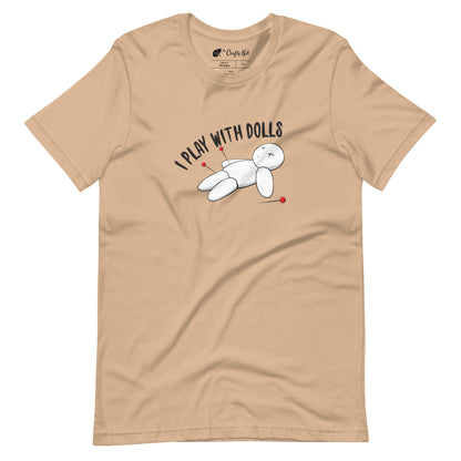 Tan t-shirt with graphic of white voodoo doll with Xs for eyes stuck with several pins and text "I PLAY WITH DOLLS"